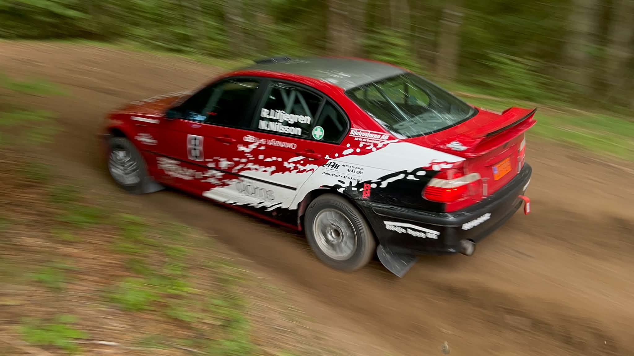 Robin Liljegrens rallybil i fart, bakifrån med rörelseoskärpa