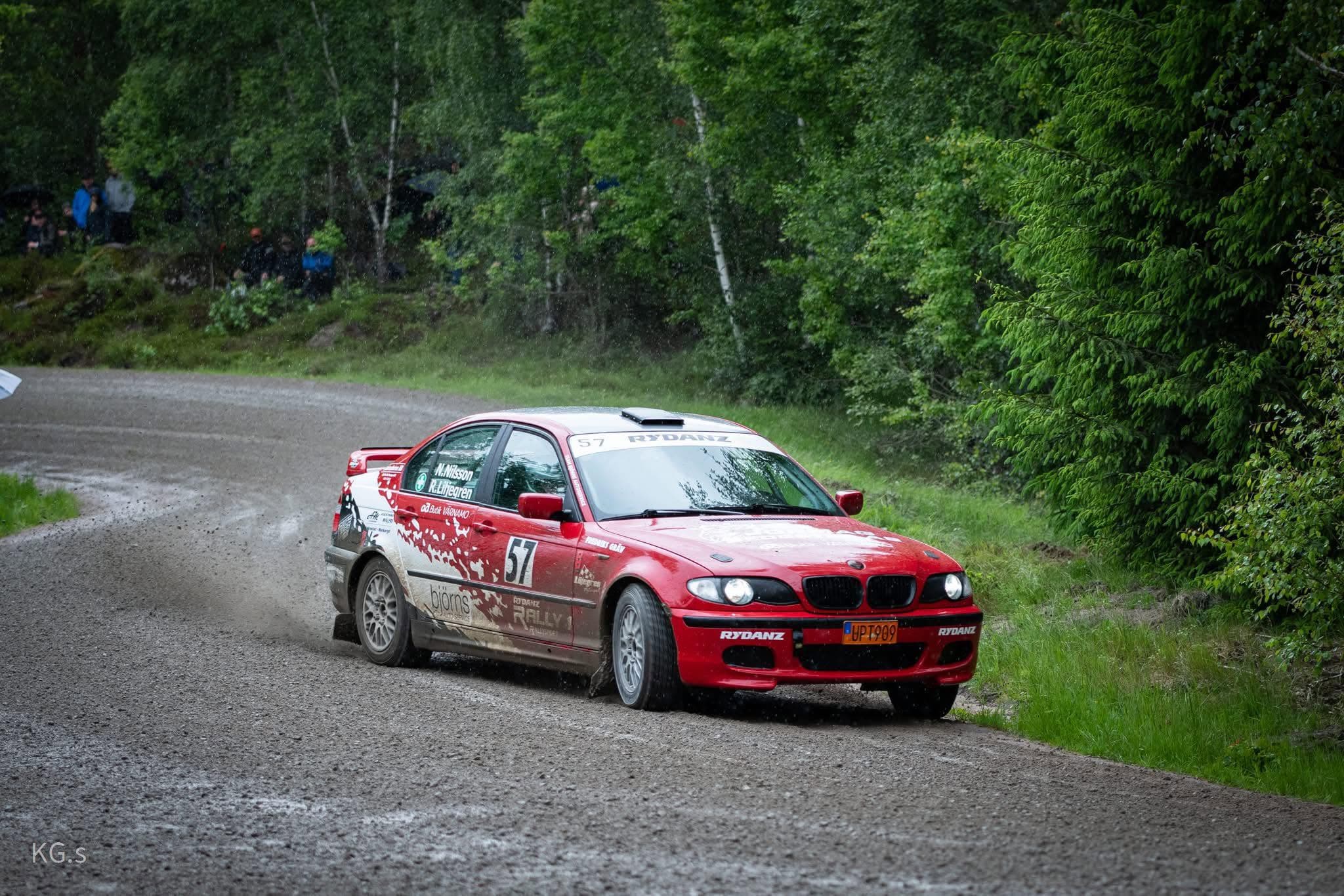 Röd BMW i Rydanz-färger på Rydanz Rally 1 i fart genom dammet på en svensk grusspecialsträcka